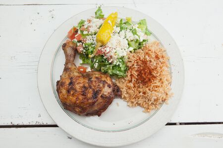 Plate of roasted chicken, saffron rice and Greek Saladの写真素材