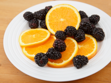 Plate of sliced navel oranges and fresh blackberriesの写真素材