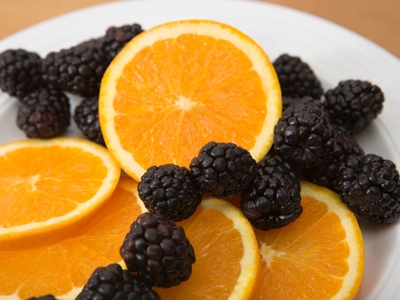 Plate of sliced navel oranges and fresh blackberriesの写真素材