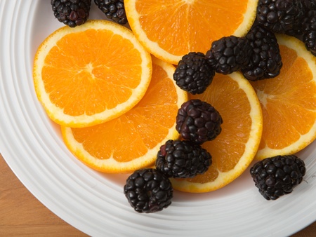 Plate of sliced navel oranges and fresh blackberriesの写真素材
