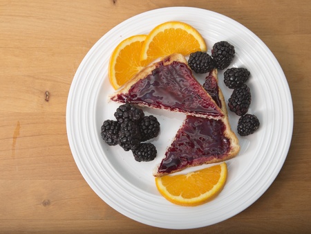 Plate of sliced toast with preserves, fresh blackberries and sliced navel orangesの写真素材