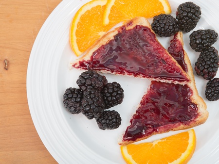 Plate of sliced toast with preserves, fresh blackberries and sliced navel orangesの写真素材