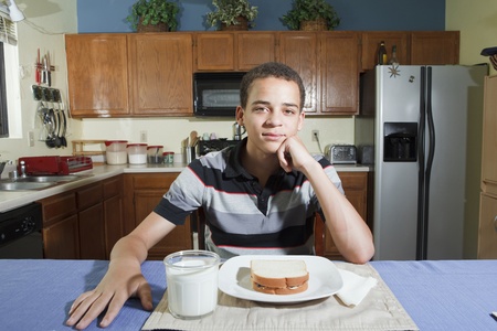 teenage mixed race boy ready to eat peanut butter and jelly sandwich in kitchen at homeの写真素材