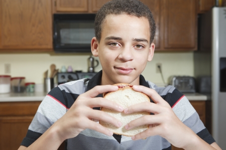 teenage mixed race boy ready to eat peanut butter and jelly sandwich in kitchen at homeの写真素材