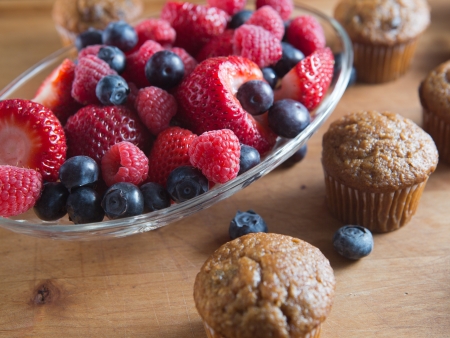 Berry and bran muffins with bowl of raspberry, strawberry and blueberryの写真素材