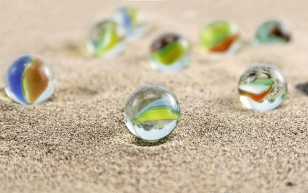 Glass marbles on sand の写真素材