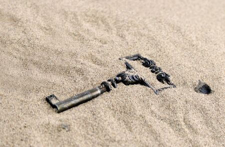 Old key in sandの写真素材