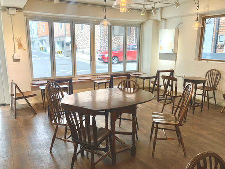 Bright and cozy cafe interior with wooden tables and chairs, illuminated by natural light through large windows.の写真素材