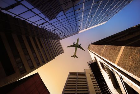 Tall city buildings and a plane flying overhead.の写真素材