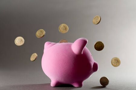 Falling coins landing on a piggy bank.の写真素材