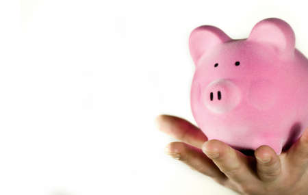 A hand holding a pink piggy bank.の写真素材