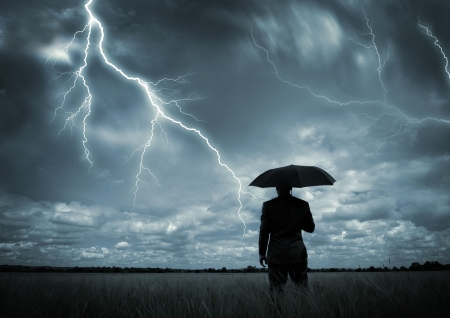 A businessman holding an umbrella in a storm.の写真素材