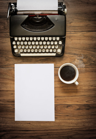 A Vintage Typewriter on a wooden table with coffee and paperの写真素材