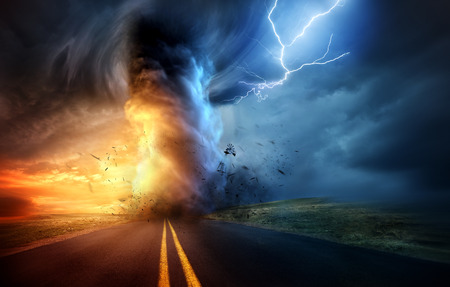 A dramatic storm at sunset producing a powerful tornado twisting through the countryside with sheet...