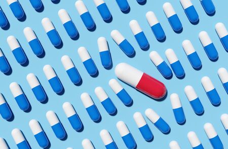 A large red pill capsule disrupting rows of blue pills. 3D render concept.の写真素材