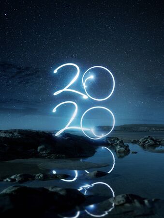 Happy New Year2020 light effect writing reflecting in water on a beach at night. Long exposure Landscape photo composite.の写真素材