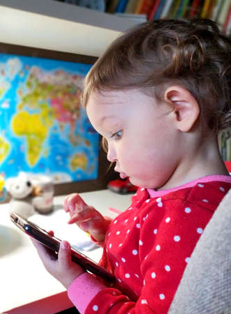 Portrait of a child in profile. Cute little girl with a smartphone.の写真素材