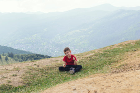 Little boy is sitting in nature. Hiking among hills and forests.の写真素材