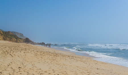 Beach by the ocean with people resting, vacation spot. Mountains, sea and waves. Travel to Europe Portugal. Praia de Vale Furado.の写真素材