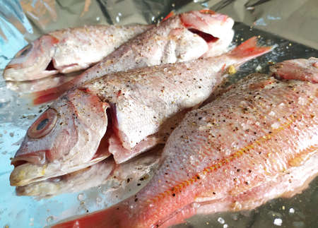 Cooking fresh fish on foil. top view and close up. Healthy sea food. Diet meal preparation photo.