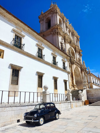 Black classic car on the background of an ancient European monastery. Vintage polished restored...