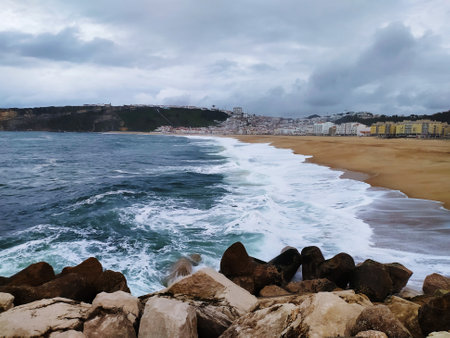 Ocean shore in stormy winter weather. Waves with splashes crash against pier.の写真素材
