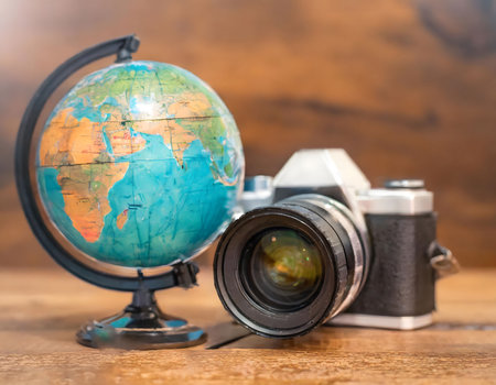 Old camera next to a world globe. Symbol of classic travel and vacation to different countries.の素材