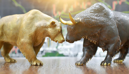 Two realistic bull figurines, symbolizing a bullish market, face each other on a wooden table, depicting a potential clash or standoff in a financial context.の素材