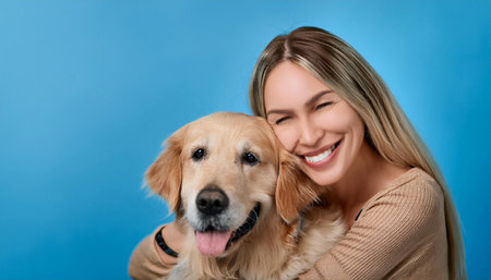 A woman joyfully hugs her golden retriever, showcasing a moment of happiness and companionship. The light blue background adds a vibrant touch, highlighting their bond as they share a smile.の素材