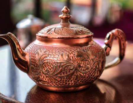 Close-up image of a copper teapot with intricate engraving and patina, symbolizing elegance, vintage style, and traditional tea-making.の素材