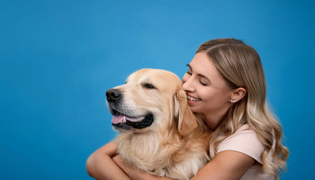 A woman joyfully hugs her golden retriever, showcasing a moment of happiness and companionship. The light blue background adds a vibrant touch, highlighting their bond as they share a smile.の素材
