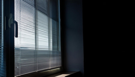 A dark room with a window showing closed blinds, providing privacy and blocking out light.の素材