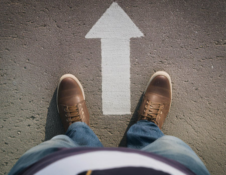 A person is positioned at the beginning of a smooth, curving pathway that leads up to a large, upward-pointing arrow. The pathway and arrow are rendered in a minimalistic blue tone, creating a serene yet motivational atmosphere. The individual appears contemplative, gazing thoughtfully at the arrow that symbolizes direction and progress, suggesting a journey towards success.の素材