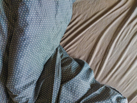 Closeup shot of a darkcolored bedsheet with a white polka dot pattern draped artfully over a...