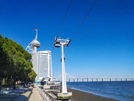 Stunning coastal cityscape featuring a cable car, modern highrise hotel, and observation tower against a vibrant blue sky. Ideal for travel, tourism, architecture, and urban lifestyle projects.の写真素材