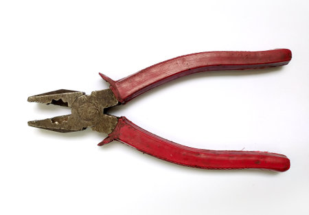 Closeup of wellused redhandled pliers against a clean white background. The image conveys a sense of...