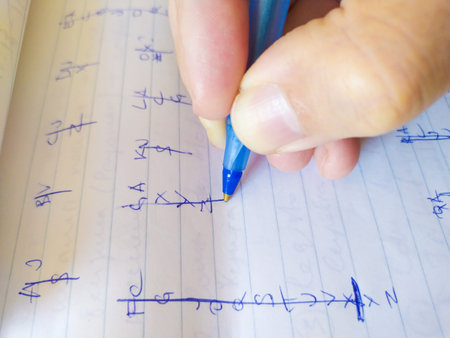 Closeup shot of a hand writing notes in a notebook with a blue pen. The image features detailed handwriting, perfect for illustrating concepts related to education, learning, or notetaking.の写真素材