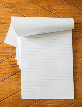 Blank lined notepad rests on a wood grain surface. Perfect for adding text, notes, or designs. Ideal...
