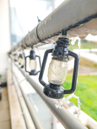 Closeup of charming miniature lantern string lights adorning a balcony railing. Perfect for adding a touch of cozy ambiance to home decor, holiday themes, or outdoor settings.の写真素材