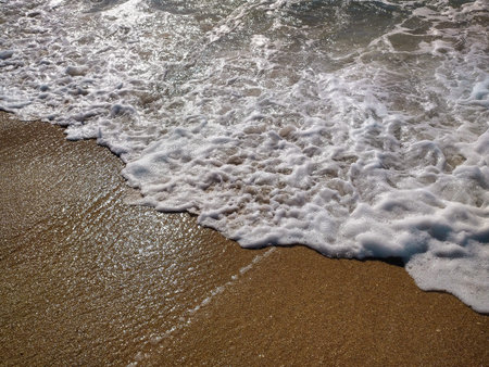 The sandy beach stretches along the coastline, where soft waves meet the shore under a bright, clear...