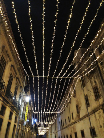 Romantic nighttime street scene. Warm fairy lights strung overhead create a magical ambiance in a historic, European-style alleyway. Perfect for travel, holiday, or romance themes.の写真素材