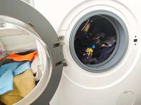 Open washing machine filled with colorful clothes. Laundry day concept. Cleaning, household chores, and routine. Use for lifestyle, home, or hygiene topics.の写真素材