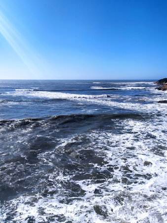 Waves crash under a vibrant blue sky. A serene and powerful ocean scene. Evokes peace, travel, and...