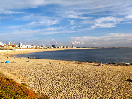 Serene coastal vista Golden sand beach meets the blue ocean under a partly cloudy sky. People enjoy leisure time. Perfect for travel, vacation and lifestyle themes.の写真素材