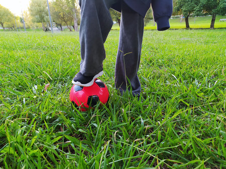 Childhood games. A foot on a soccer ball in green grass. Fun, sport and outdoor recreation concept....