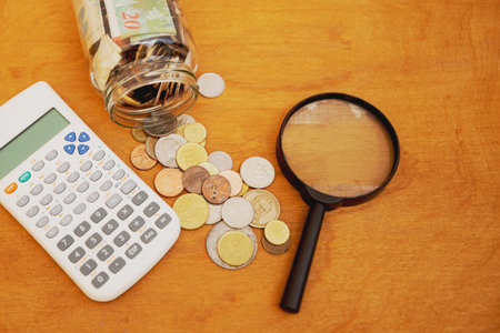 Statistics and research table on finance and business and money with calculator, magnifying glass, coins and banknotesの写真素材