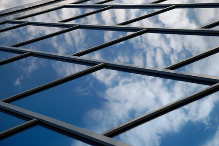 The facade of a modern building from blue glass reflects the skyの写真素材