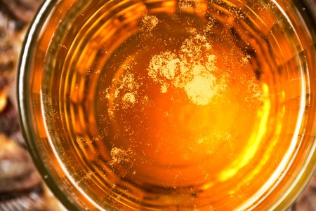 The dark stylized surface of beer glass with fish backgroundの写真素材