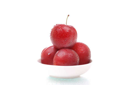 Ripe and juicy plums with drops on a plateの写真素材