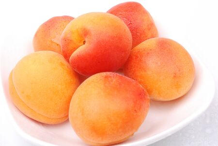 Ripe and juicy apricots on a white plateの写真素材
